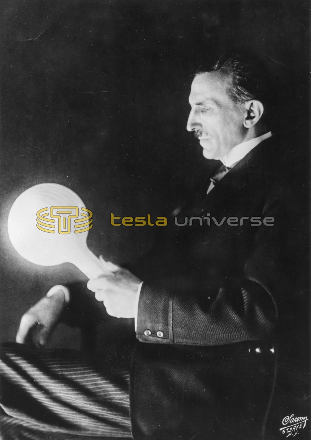 Nikola Tesla holding filamentless bulb lit by wireless power