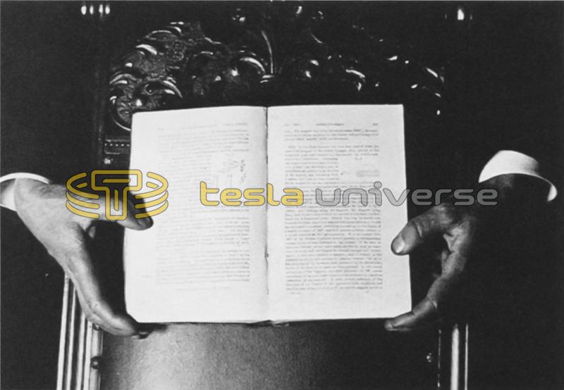 The hands of Tesla holding a book for a photo using fluorescent light