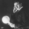 Nikola Tesla posing with an early fluorescent lamp he developed