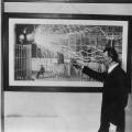 Nikola Tesla pointing to a photograph of his Colorado Springs Experimental Station